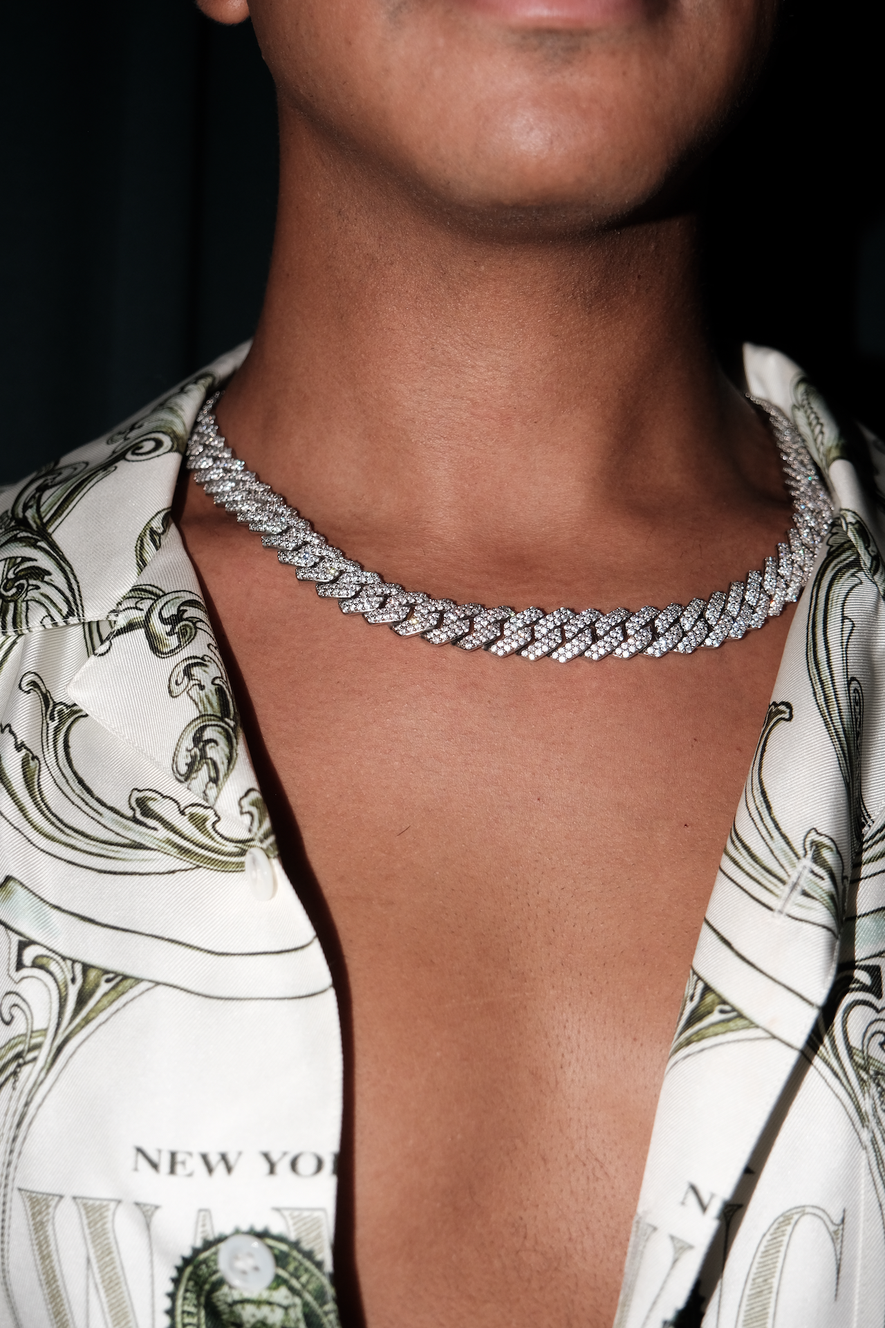 Person wearing the Owner's Crystal Cuban Chain in silver tone with a printed silk shirt